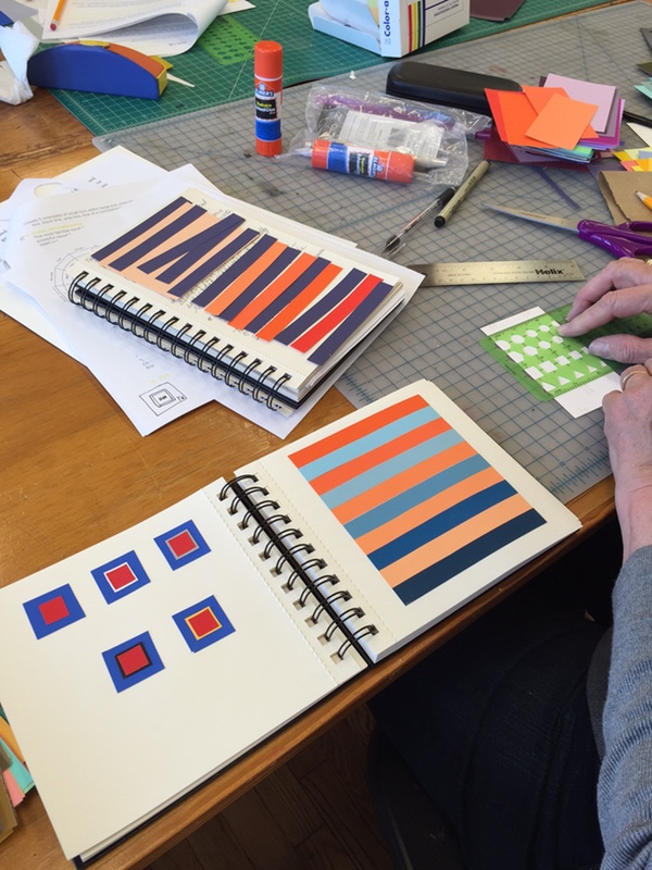 A person designing a project with books of color samples and color scheme examples